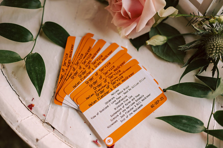 Order of service at  wedding printed on orange and white train tickets 