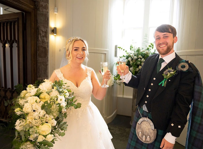 a bride and groom stand next to each other raising a glass of champagne each