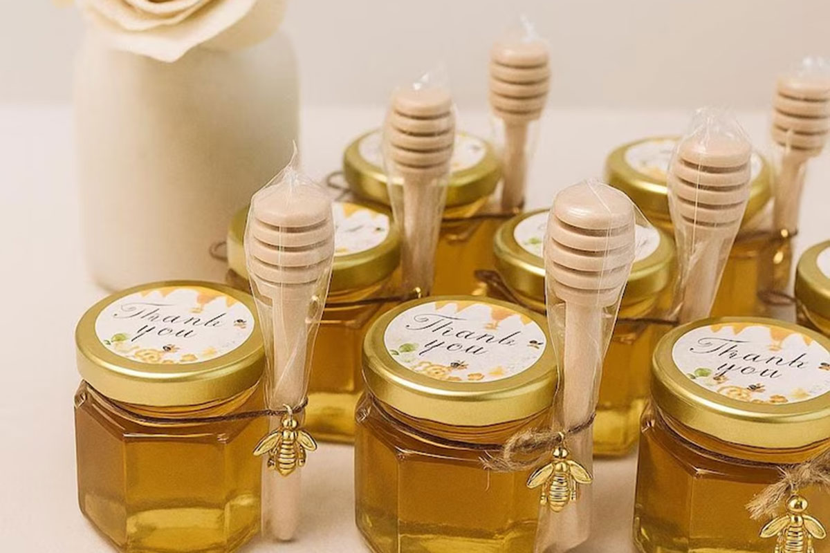 Mini honey jar wedding favour styled with lavender, honeycomb and a wooden honey dipper