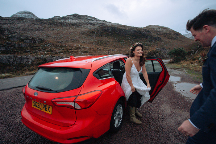 Bride emerges out of a red car