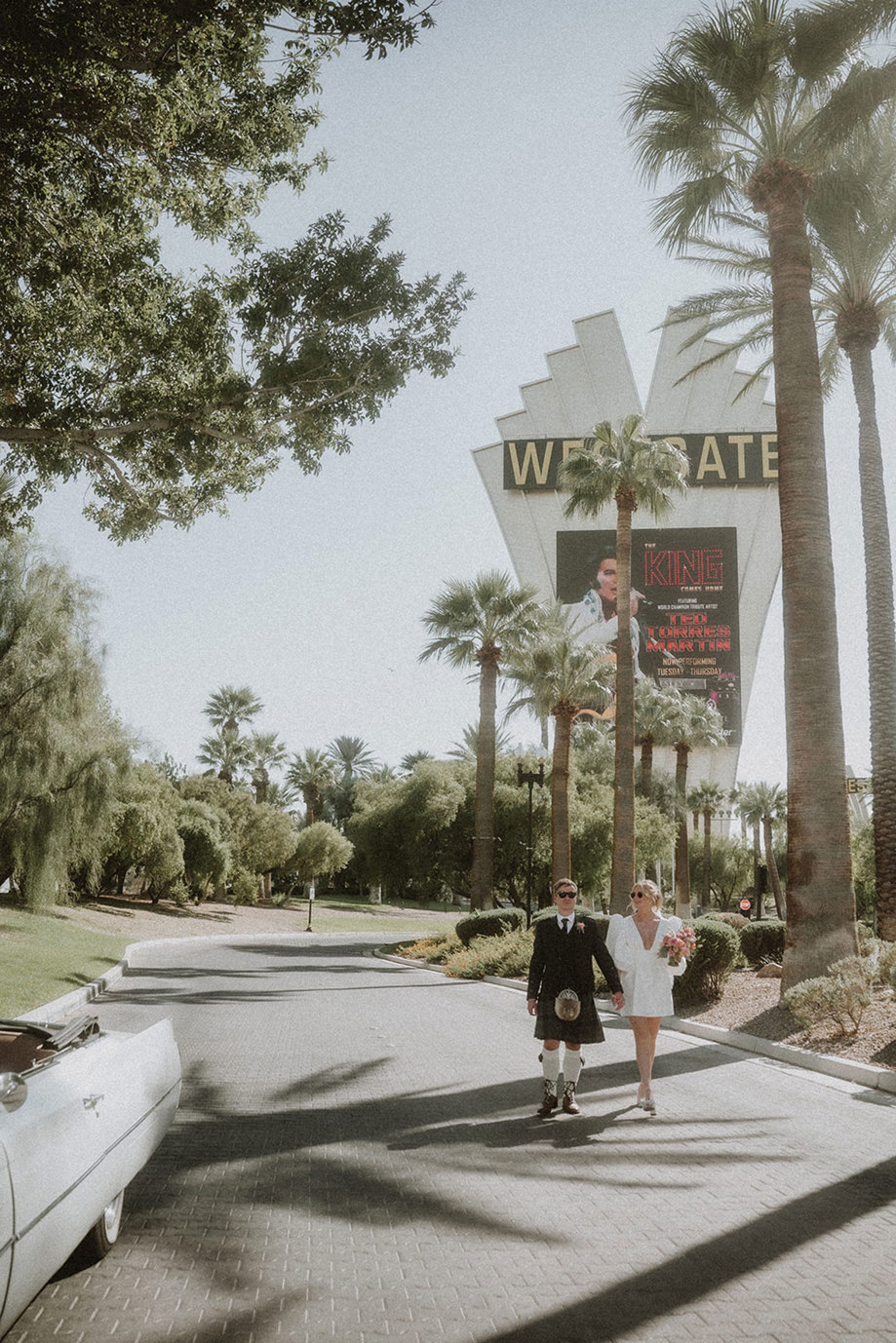 bride and groom walk under palm trees after getting married in las vegas