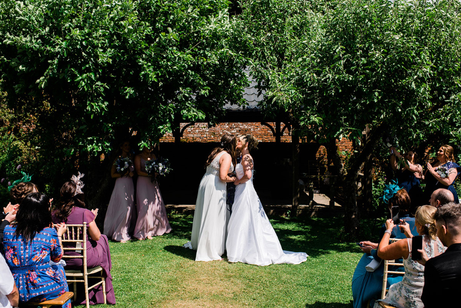 Brides kiss at the top of the aisle