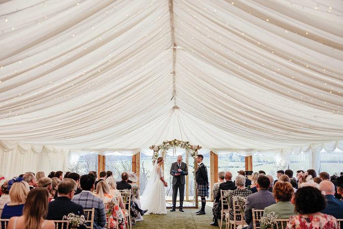 a wedding ceremony in a fairylight covered marquee