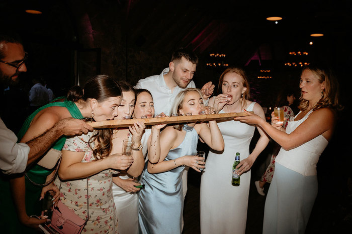 a row of people drinking shots from a large wooden paddle