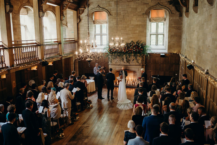 A bride and groom in the ballroom at Achnagairn Castle with rows of people in front of them