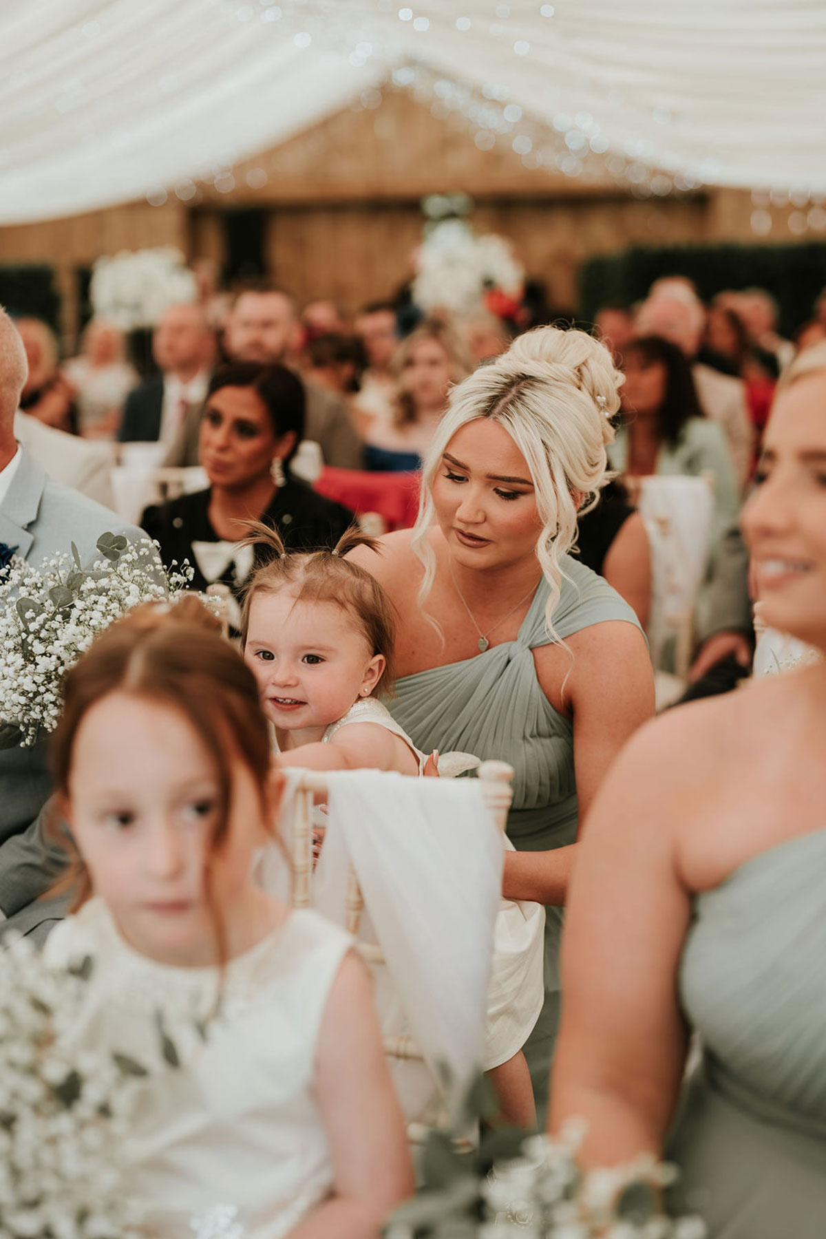 Wedding guests seated inside a marquee during the ceremony.