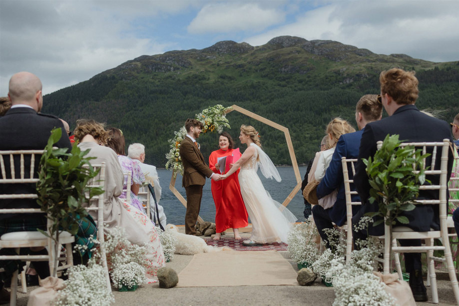 bride and groom hold hands as their celebrant conducts outdoor ceremony at carrick castle estate