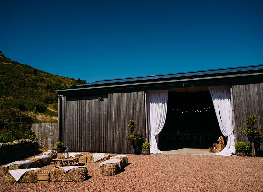 outside of a barn on a sunny day with white curtains over the entrance