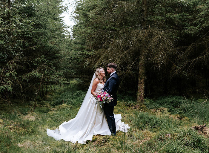 a bride and groom posing in a green forest setting