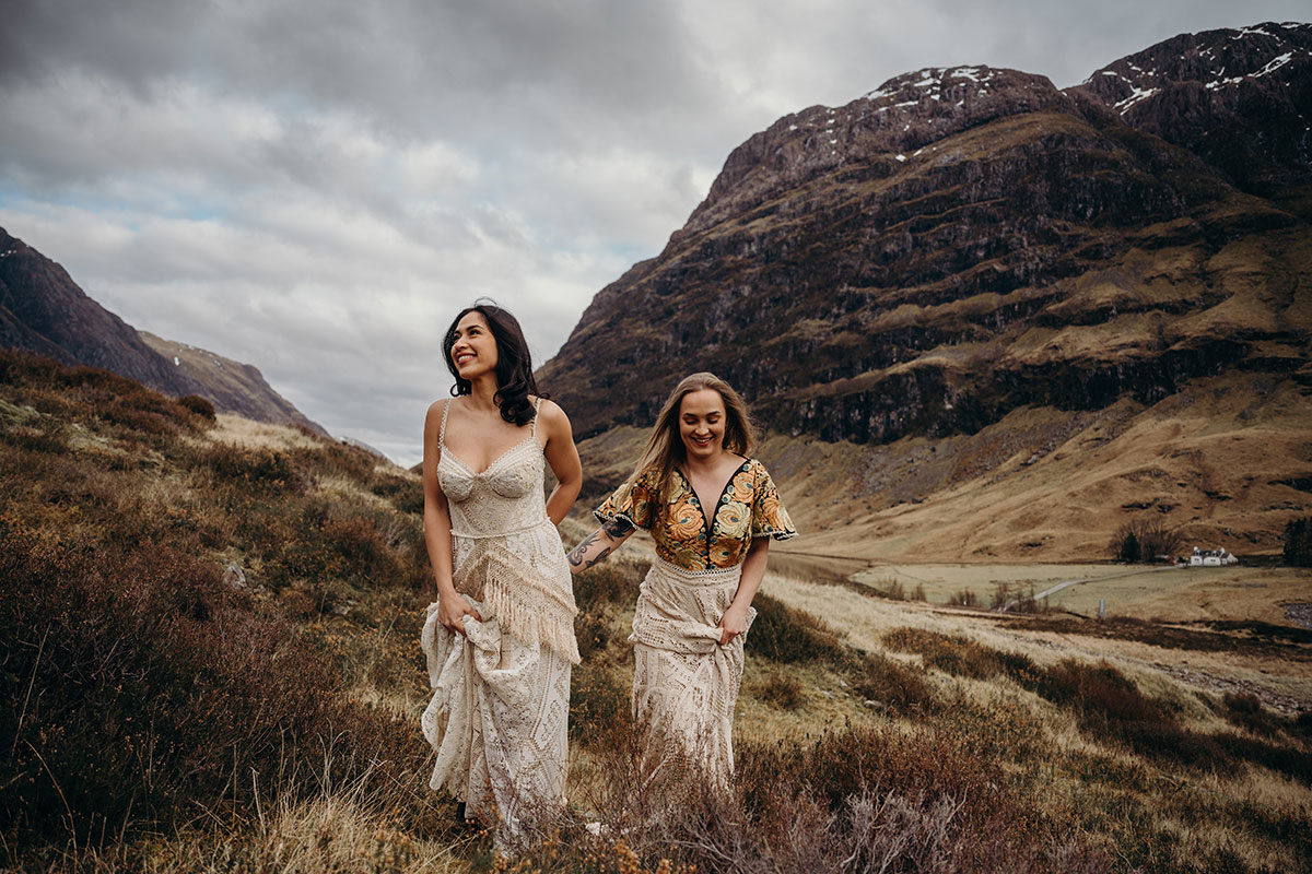 Couple laughing together during a relaxed Glencoe elopement shoot, wearing lace wedding outfits in the Scottish Highlands.