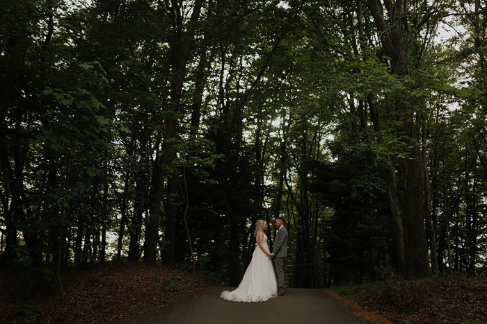 A Bride And Groom Pose Under A Canopy Of Green Trees At Forbes Of Kingennie