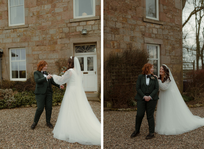 first look of two brides outside a Georgian-style building, one wearing a wedding dress, one wearing a dark green suit