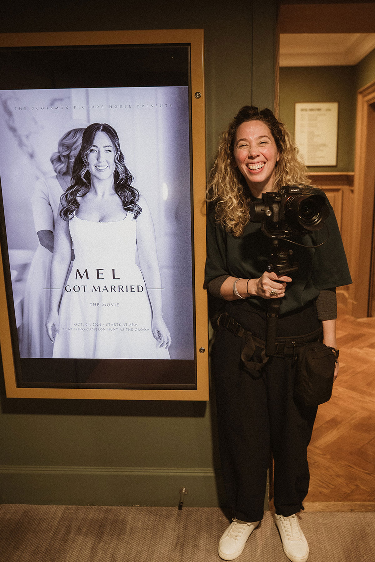A person smiling next to a poster at the Scotsman Picturehouse