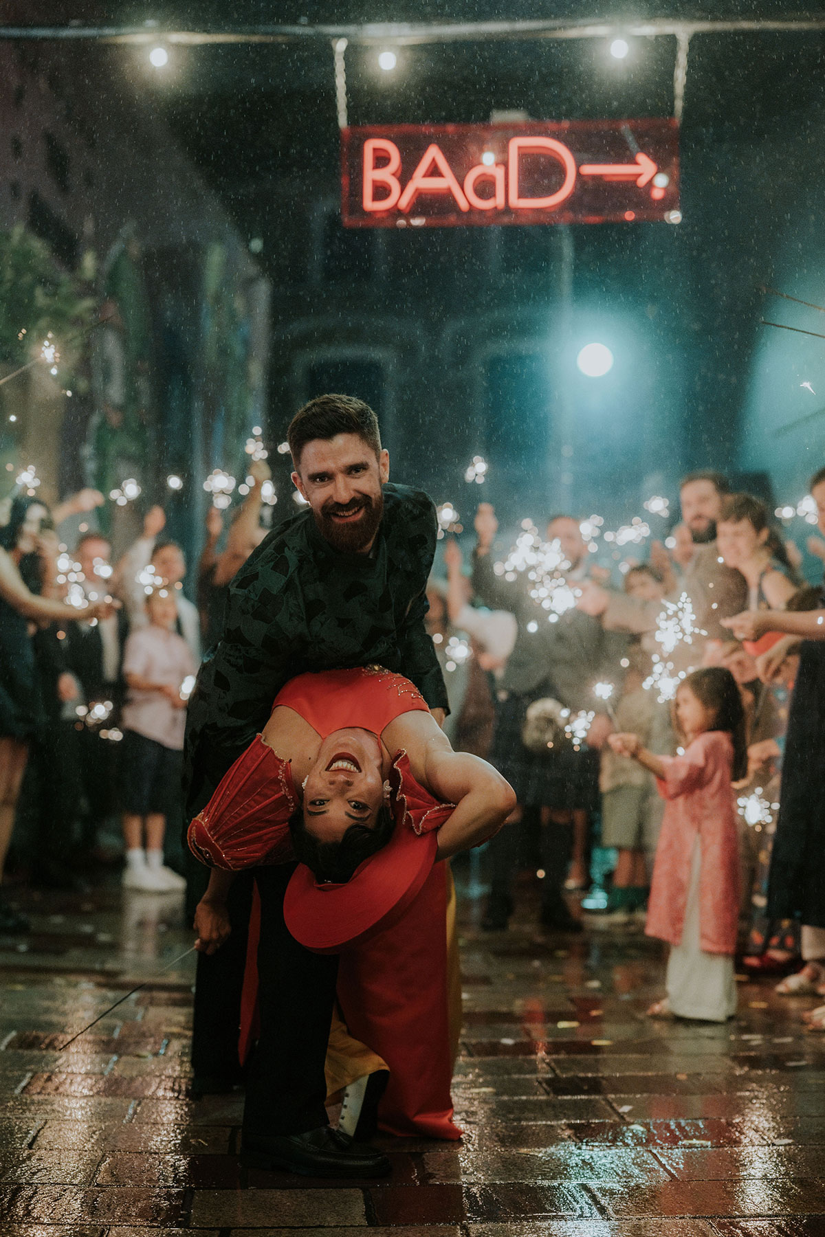 Groom dipping bride during sparkler exit outside Barras Art and Design Glasgow at night