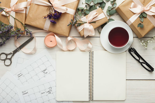 wedding planning set up with calendar, blank notebook, flowers and tea