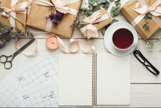 wedding planning set up with calendar, blank notebook, flowers and tea