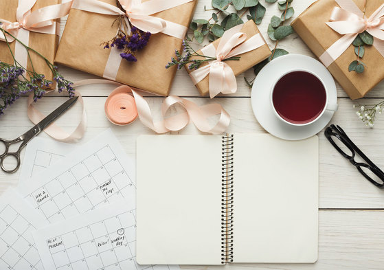 wedding planning set up with calendar, blank notebook, flowers and tea