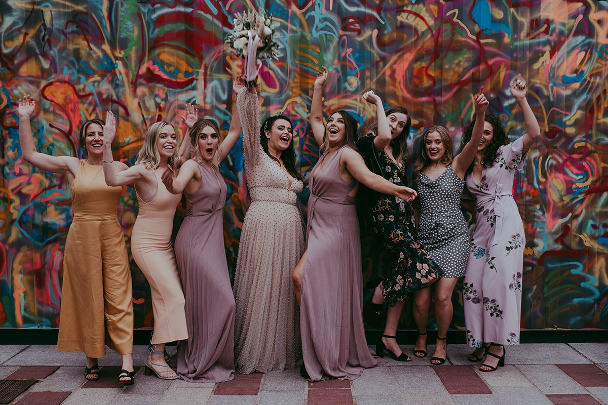Wedding Group Portrait Against Colourful Mural At Barras Art And Design