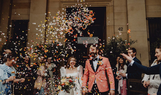 A bride and groom walking down the street with confetti falling.