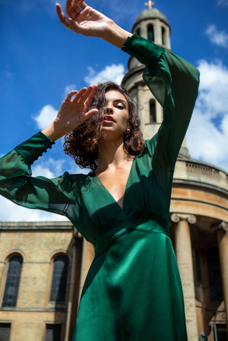 a woman wearing a green satin dress with long sleeves and a v-neck. Pearl by Andrea Hawkes.