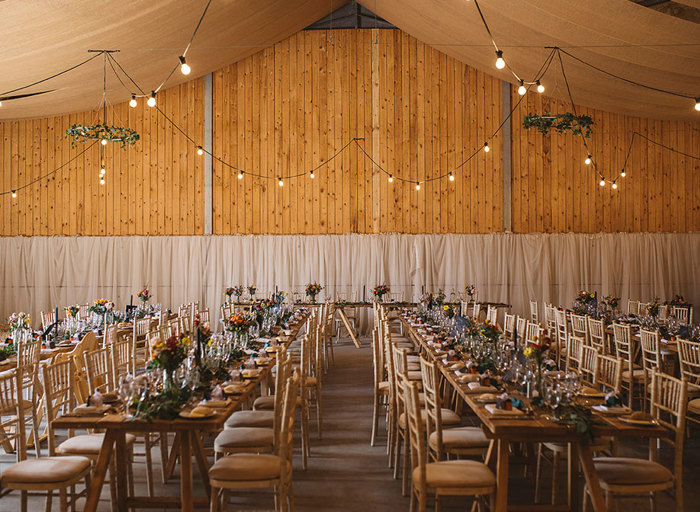 inside a wooden barn lined with long tables and chairs 