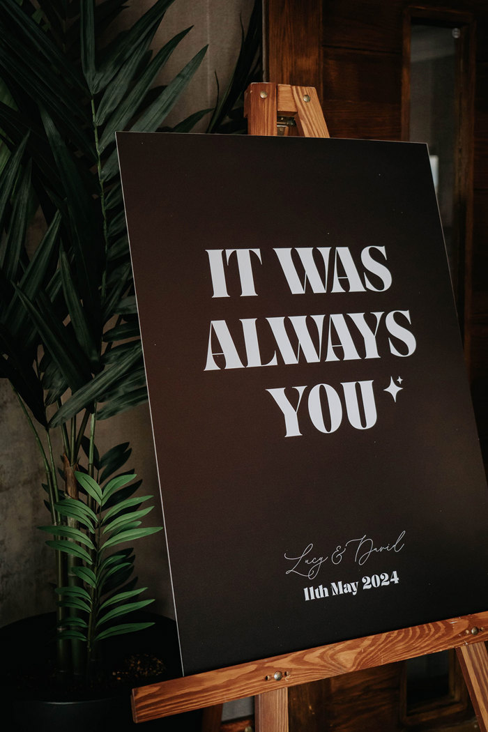 a black sign with white text that reads "it was always you"