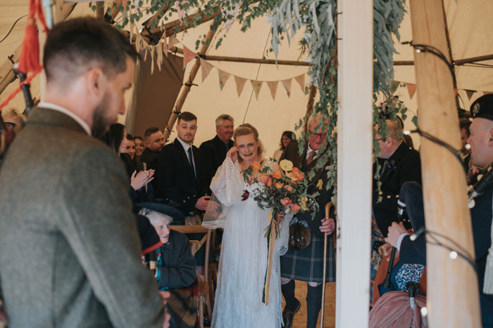 Bride cries as she spots the groom playing bagpipes at the top of the aisle