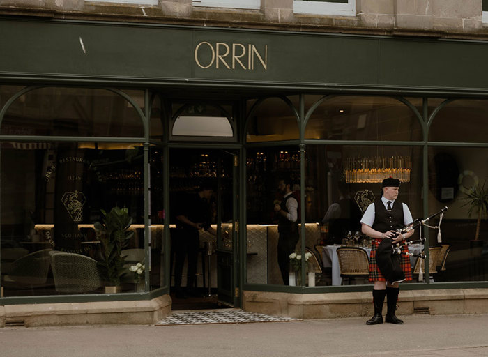 exterior of Orrin restaurant in Elgin with bagpiper standing outside