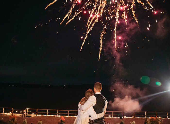 a bride and groom watching fireworks in the night sky