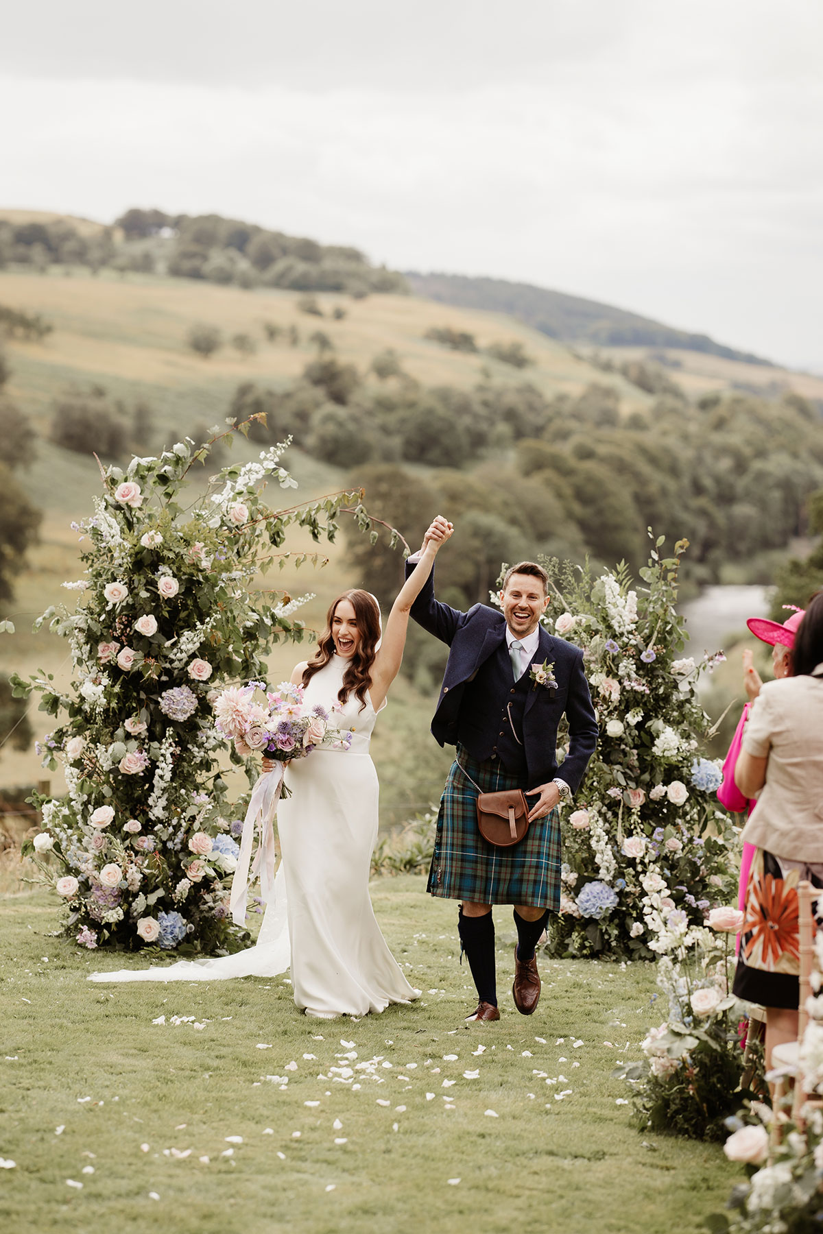 a cheering bride and groom after their outdoor wedding ceremony at Netherdale House