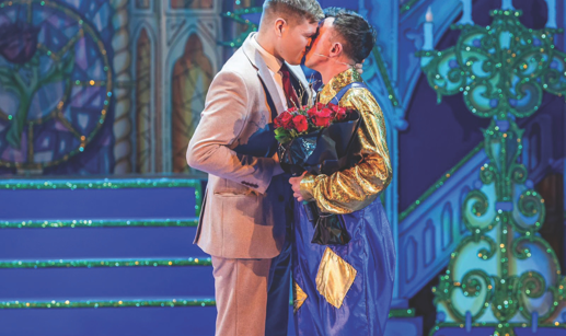 Two men kissing on stage holding red roses