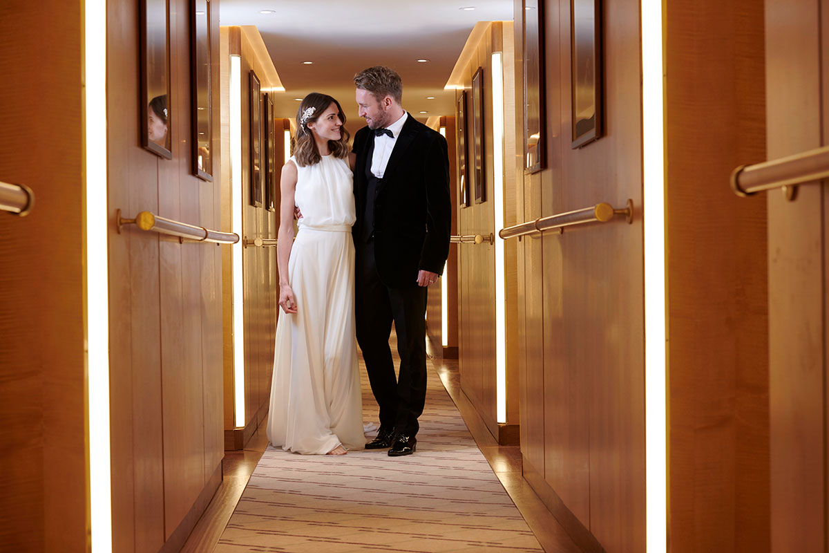 Bride and groom walking through Fingal’s softly lit cabin corridor in Edinburgh, captured after their wedding ceremony