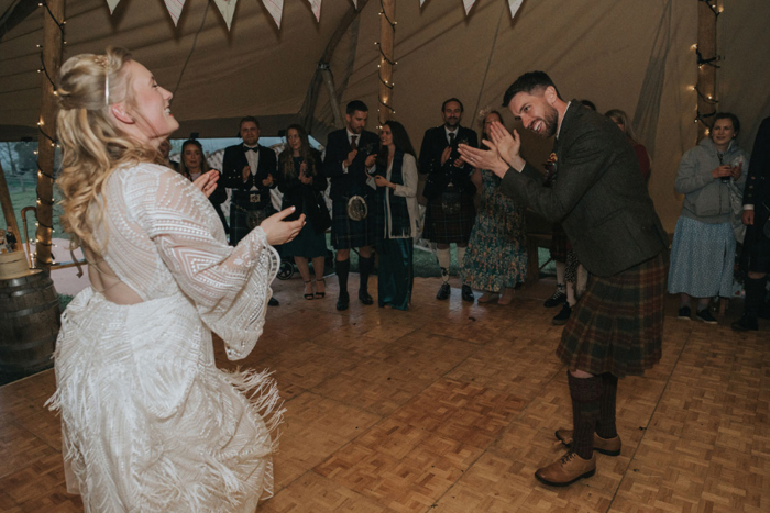 Bride and groom clap their hands on the dancefloor