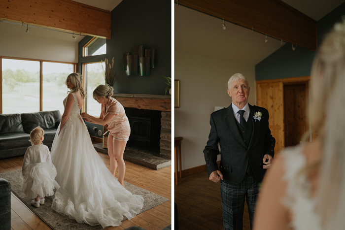 A Bride Standing On A Rug As Person Helps Fasten Button On Her Dress And Young Child Looks On On Left And Person Wearing Tartan Trouser Outfit On Right
