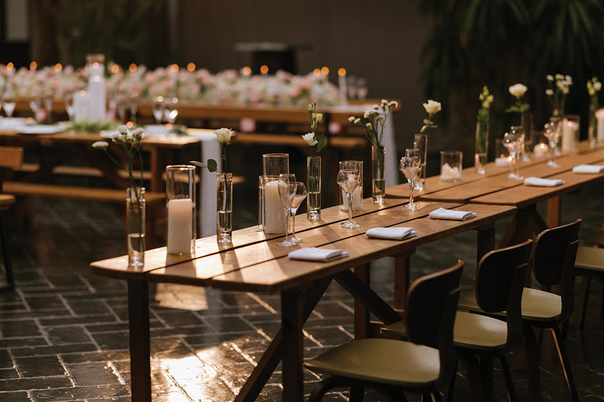 Long wooden wedding tables with candles and minimalist floral centrepieces set for a reception at BAaD Glasgow wedding venue