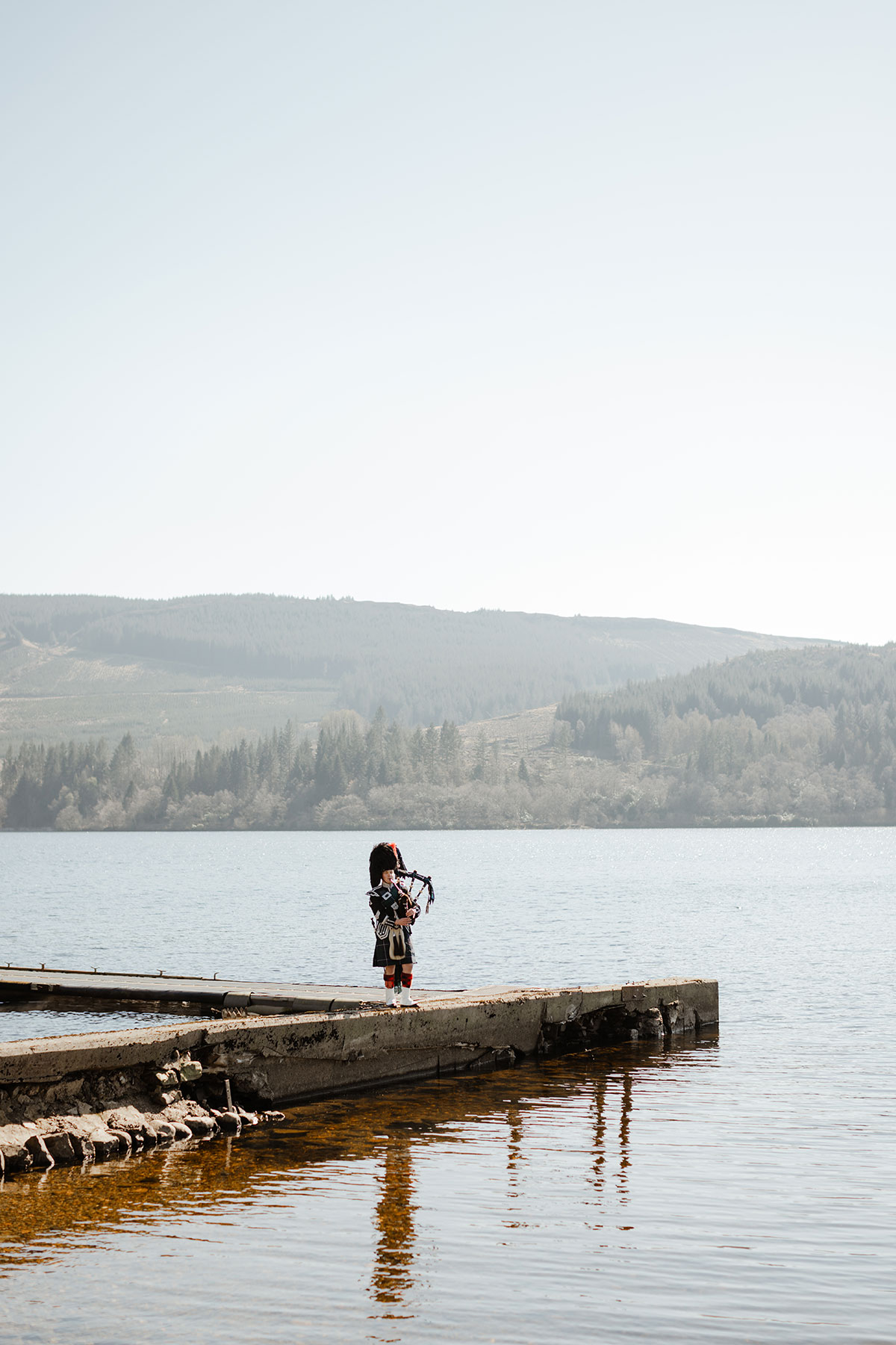 Piper playing bagpipes by the loch