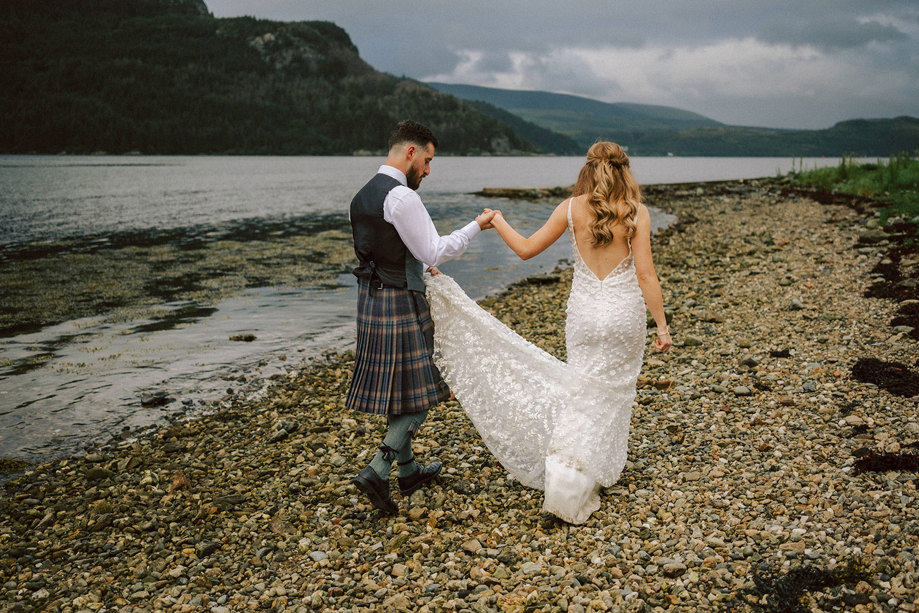 bride and groom walk along the beach holding hands during wedding at carrick castle 
