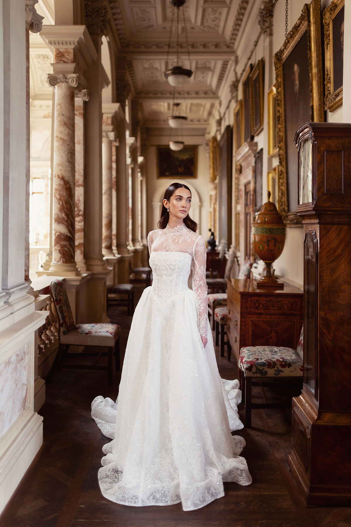 Grand corridor at Gosford House with marble columns, framed portraits and period furniture.