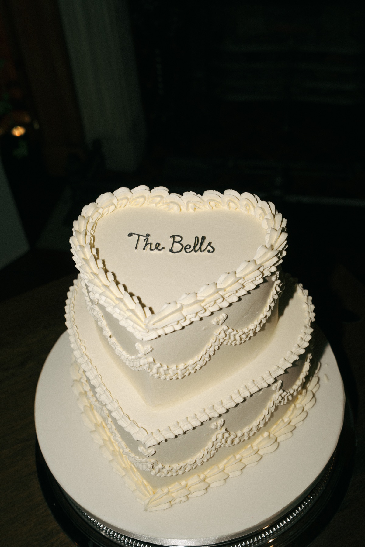 Two-tier heart-shaped white wedding cake by Liggy’s Cake Company with vintage-style piping and ‘The Bells’ lettering at Barnbougle Castle.