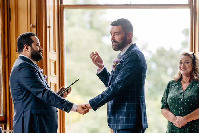 Grooms hold hands during wedding ceremony