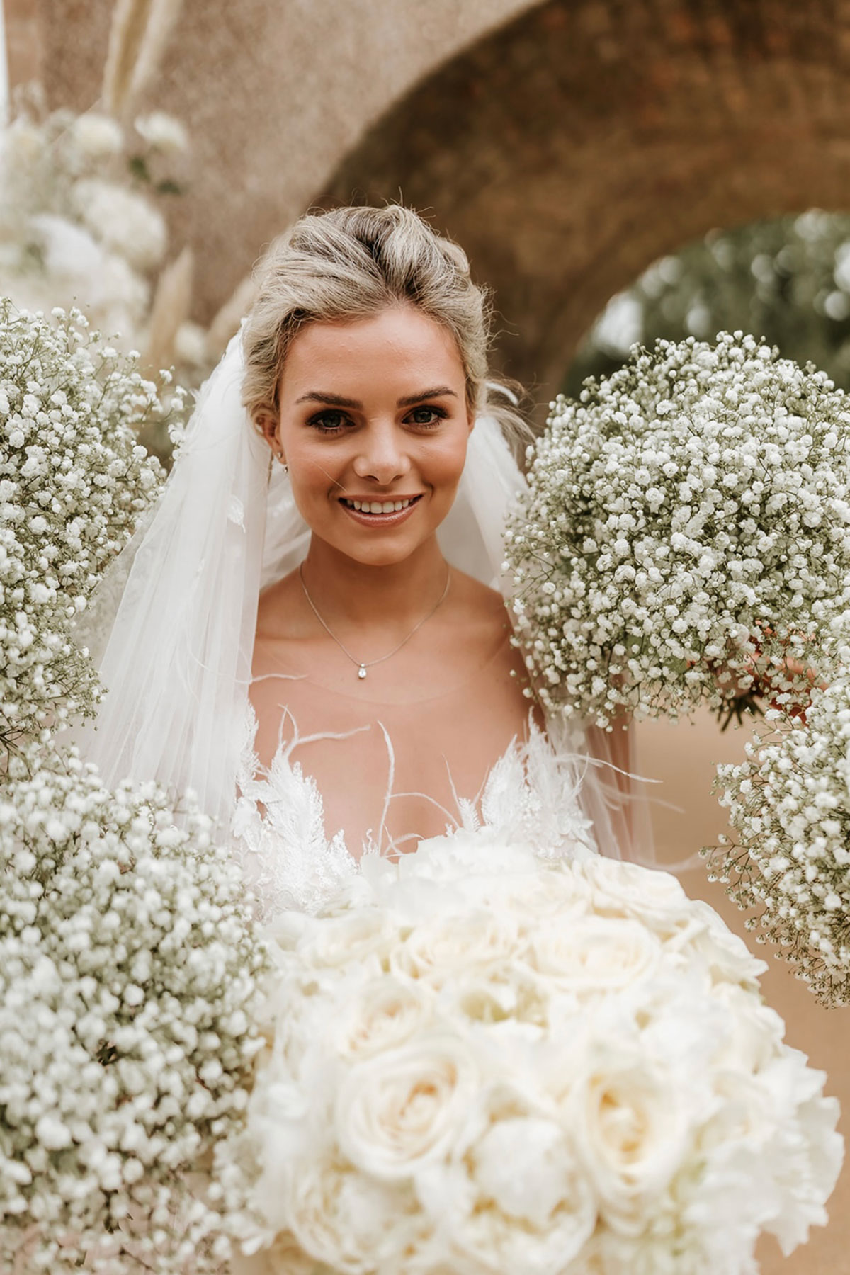 bride smiles as bridesmaids holds bouquets around her