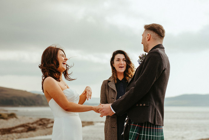 bride and groom laugh with celebrant during outdoor wedding at dougarie boathouse
