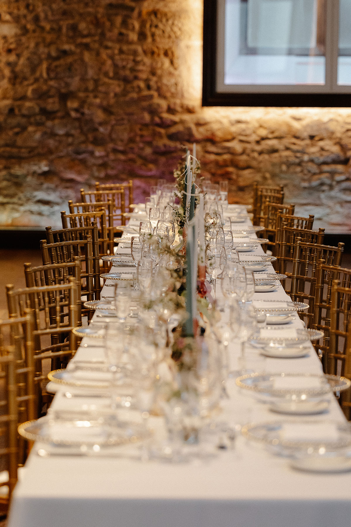 Elegant long wedding tables at Virgin Hotels Edinburgh’s Greyfriars Hall, decorated with gold chairs, candles and soft floral arrangements.