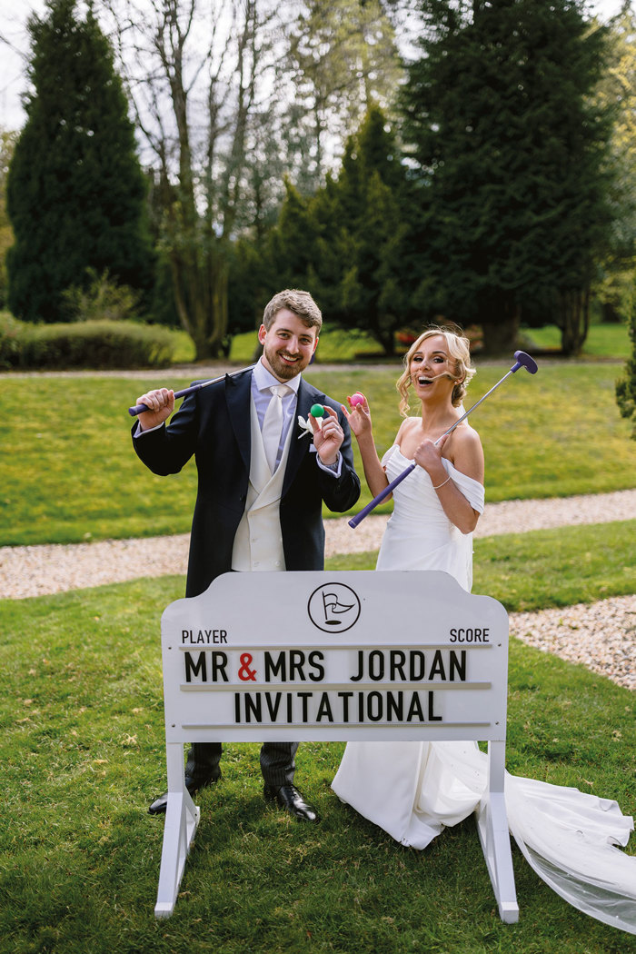 a bride and groom posing with a sign at Mar Hall.