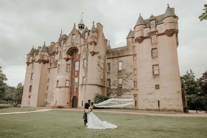 bride and groom kiss as her veil floats in the wind at fyvie castle
