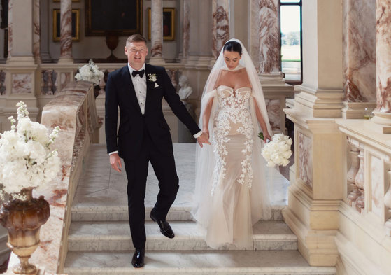 a bride wearing Berta Privee wedding dress and a groom wearing a black tuxedo. They are walking down a marble stone staircase at Gosford House.