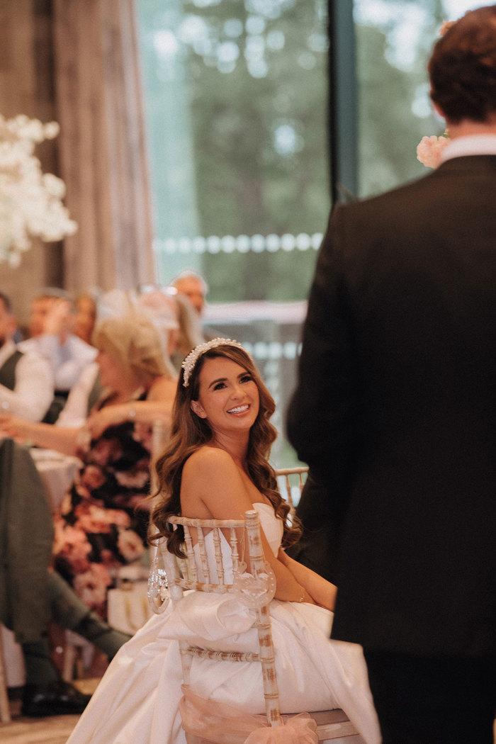 a smiling bride sitting on a Chiavari chair.