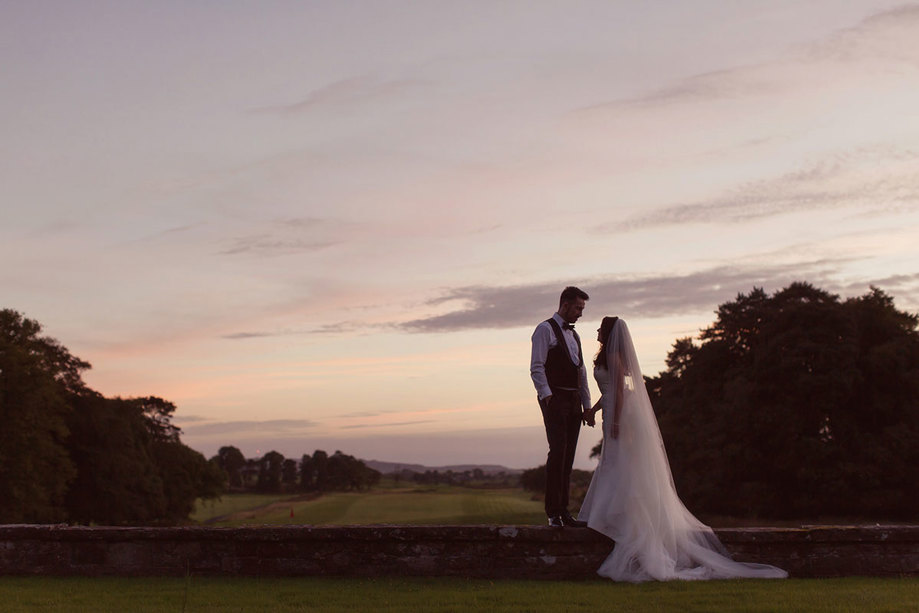 bride and groom hold hands outdoors during wedding at rowallan castle