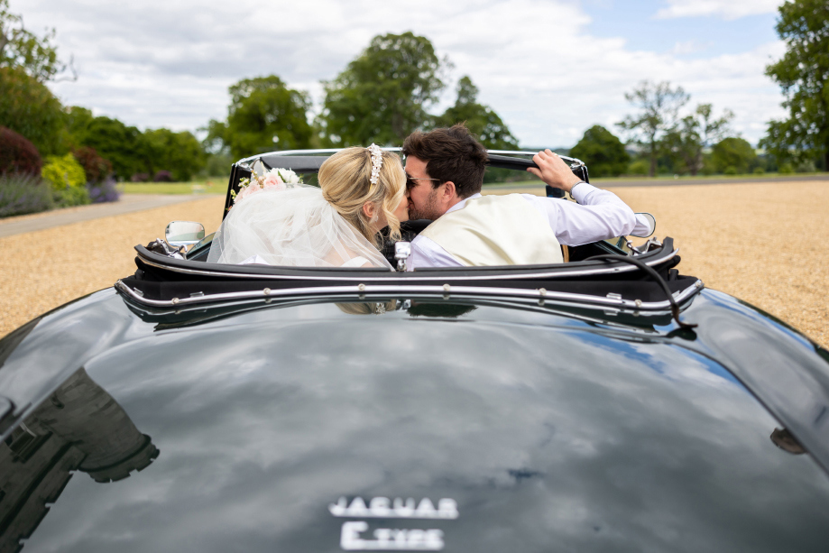 Couple kiss in black convertible Jaguar car