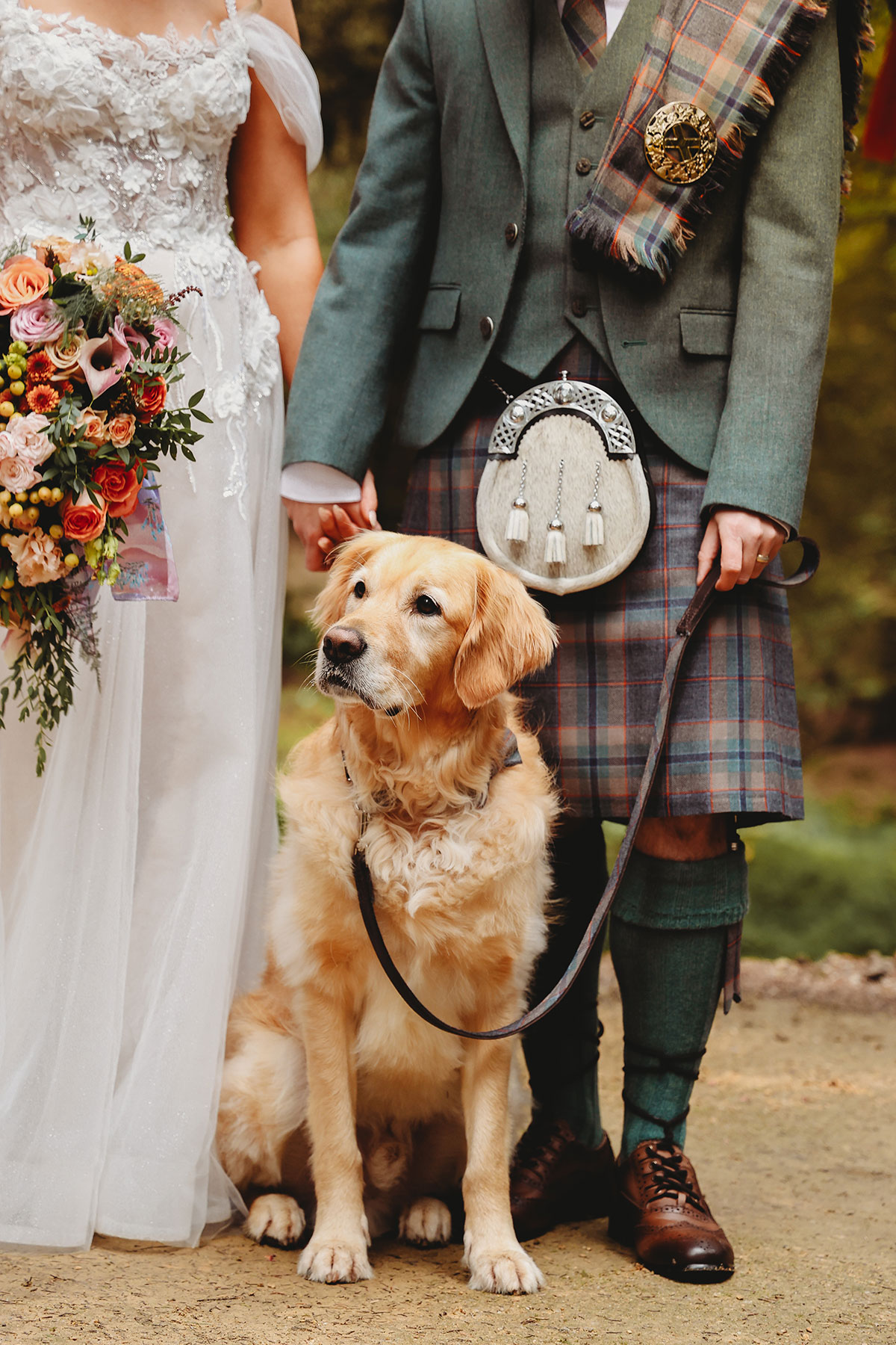 Golden retriever sitting between the bride and groom during wedding portraits at a Scottish woodland venue